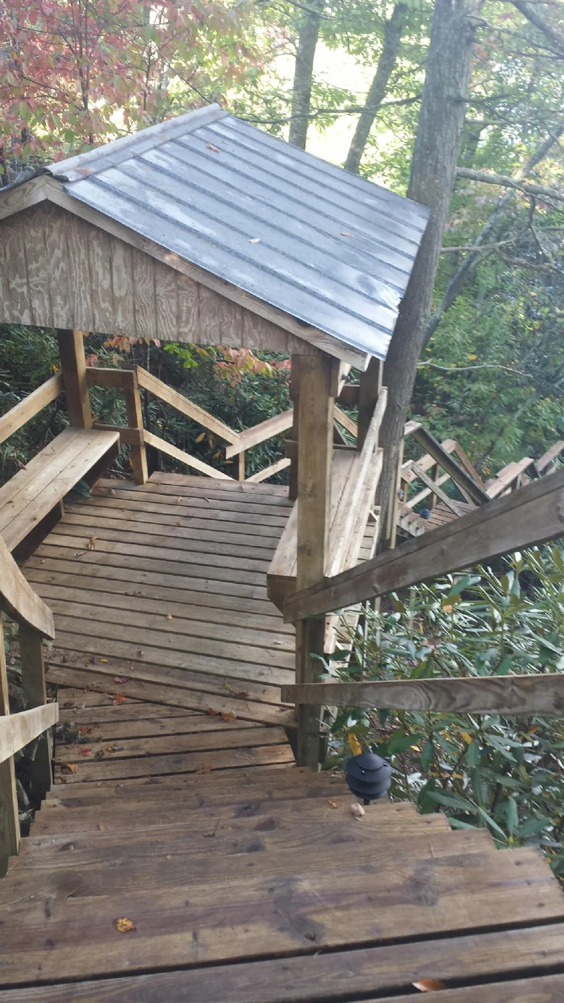 Metal roofed shelter over wooden steps on a wooded walkway — Skylight Repair & Installation work by our crew in Hollis
