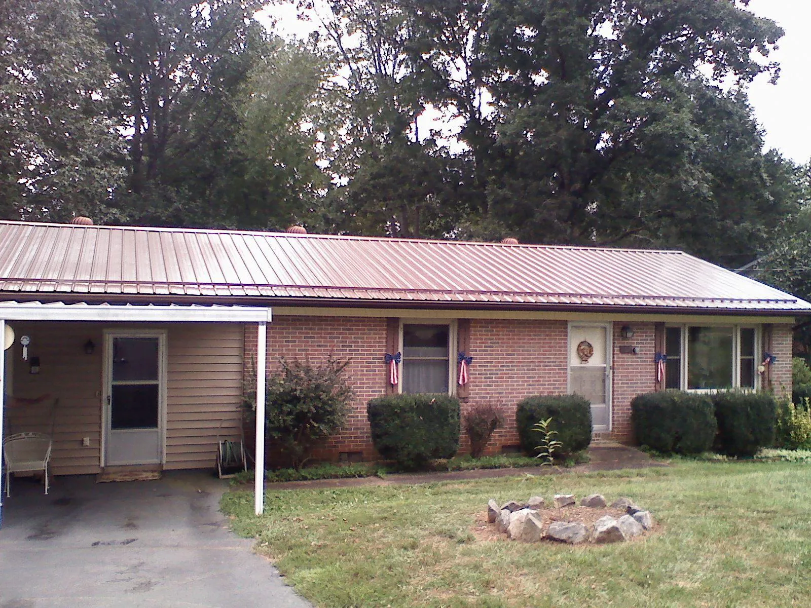 Bronze metal roof and carport on a brick ranch home — Roof Repair work by our crew in Hollis